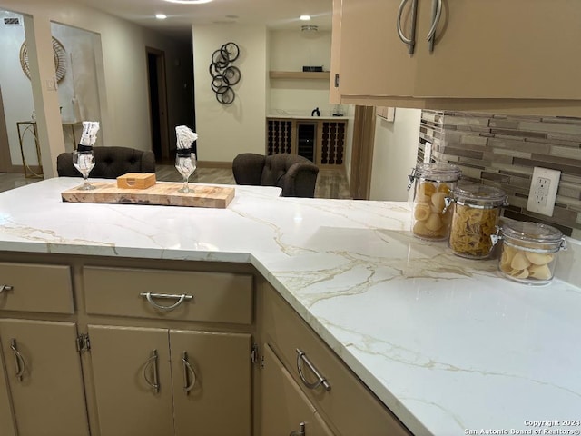 kitchen featuring kitchen peninsula, light stone counters, and tasteful backsplash