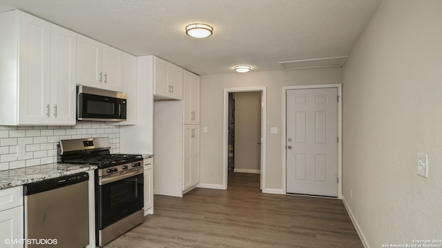 kitchen featuring appliances with stainless steel finishes, light stone counters, and white cabinetry