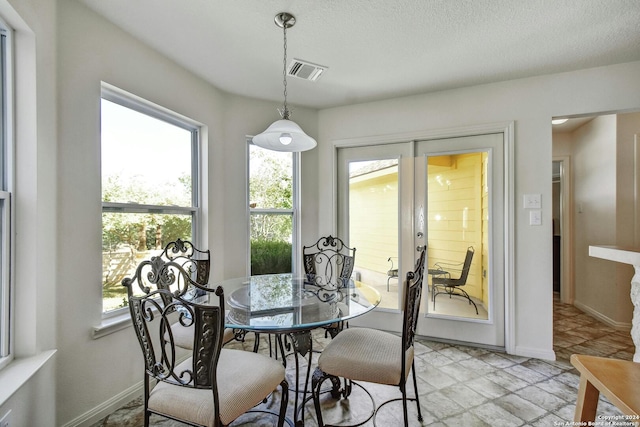 dining area with french doors, a textured ceiling, and a wealth of natural light