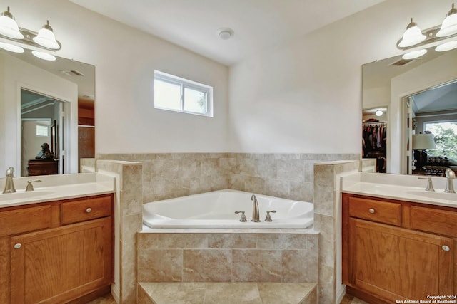 bathroom with vanity, tiled bath, and plenty of natural light