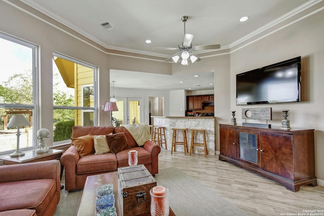 living room featuring crown molding, light hardwood / wood-style floors, a healthy amount of sunlight, and ceiling fan