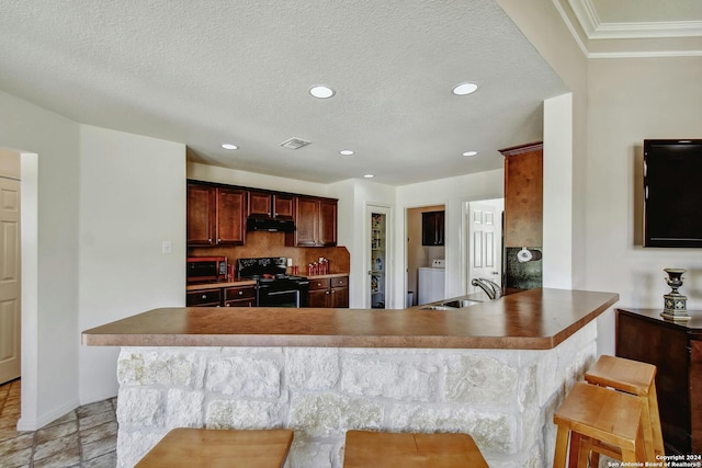 kitchen featuring kitchen peninsula, sink, a breakfast bar, black electric range, and a textured ceiling