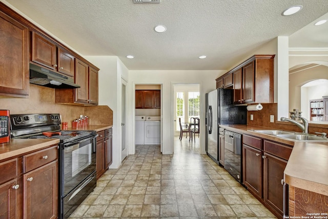 kitchen featuring sink, a textured ceiling, black appliances, and washing machine and dryer