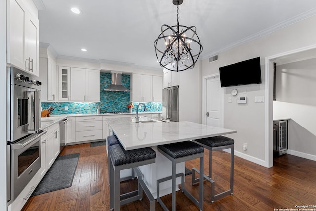 kitchen featuring visible vents, ornamental molding, stainless steel appliances, a sink, and wall chimney exhaust hood