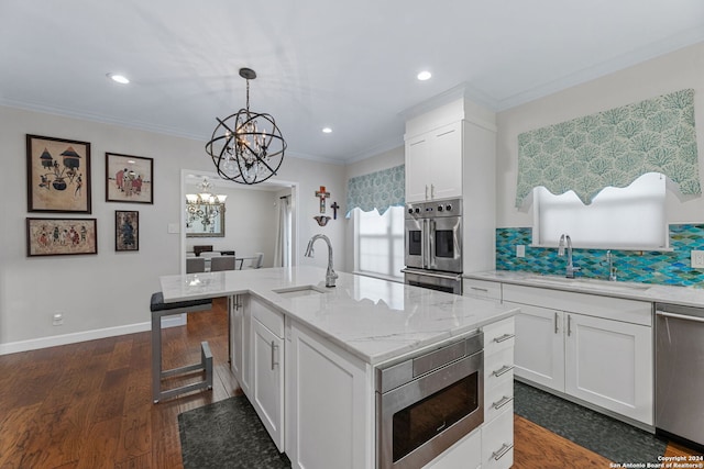 kitchen with appliances with stainless steel finishes, white cabinets, sink, and a center island with sink