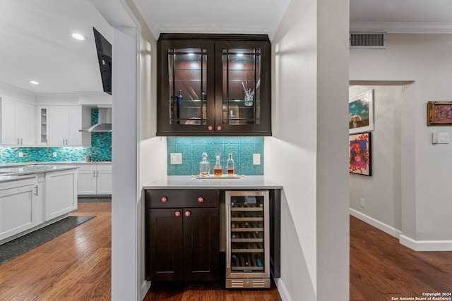 bar featuring tasteful backsplash, beverage cooler, white cabinetry, dark hardwood / wood-style floors, and ornamental molding