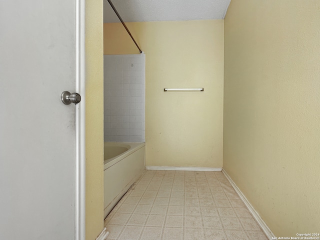 bathroom with tiled shower / bath and a textured ceiling