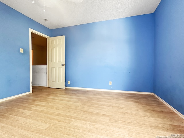 unfurnished room featuring a textured ceiling and light wood-type flooring