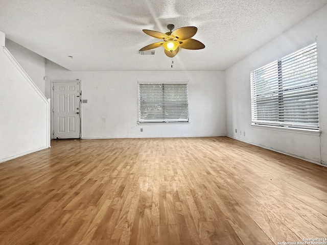 unfurnished living room featuring light hardwood / wood-style floors, a textured ceiling, and ceiling fan