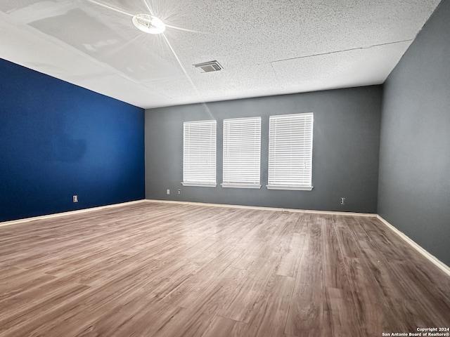 empty room with wood-type flooring and a textured ceiling