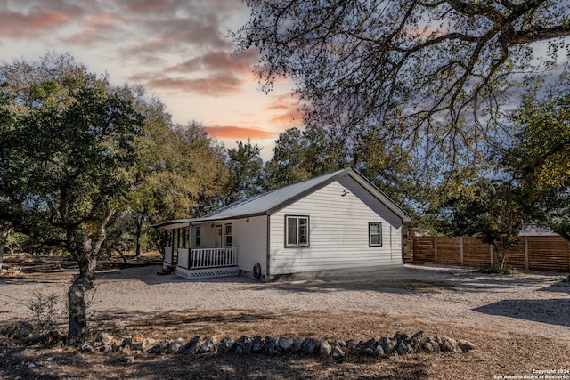 back house at dusk featuring covered porch