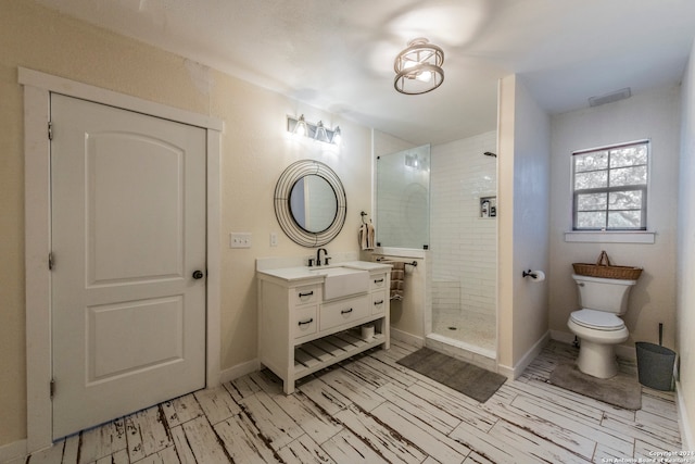 bathroom featuring a tile shower, vanity, and toilet