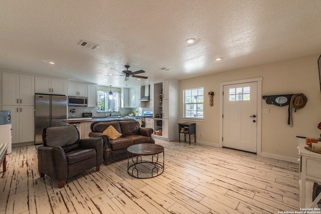 living room featuring a textured ceiling, plenty of natural light, and ceiling fan