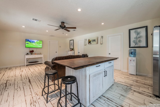 kitchen featuring a center island, light hardwood / wood-style flooring, a kitchen bar, and wood counters