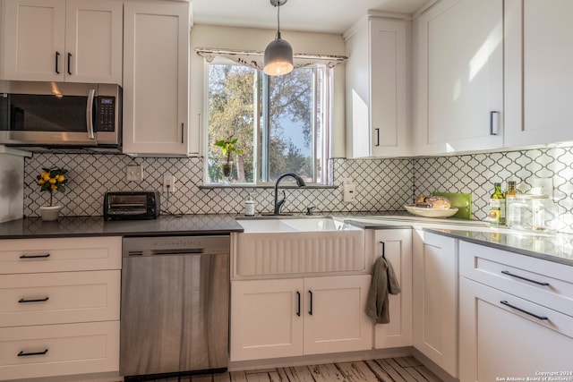 kitchen with white cabinetry, decorative light fixtures, and stainless steel appliances