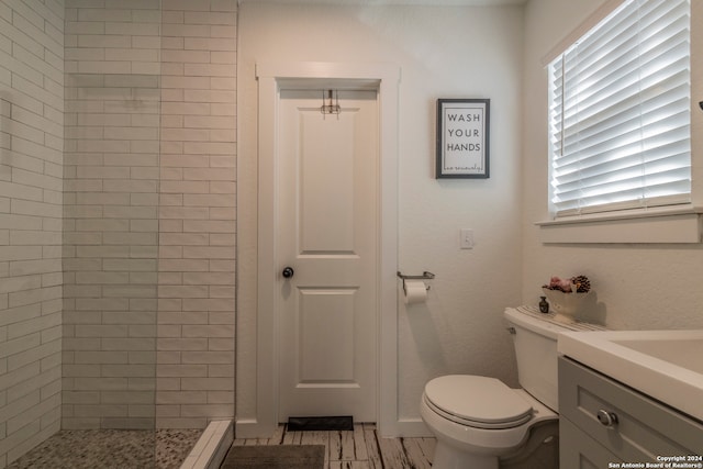 bathroom featuring a tile shower, toilet, and vanity