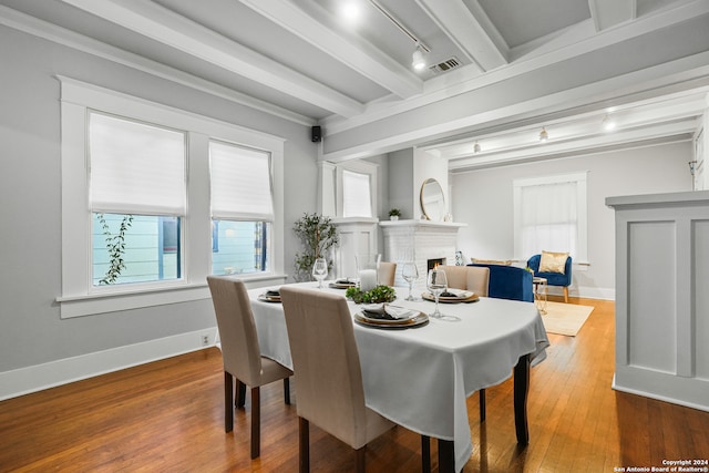 dining room with crown molding, hardwood / wood-style floors, beam ceiling, and track lighting