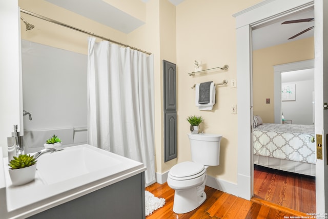 bathroom with toilet, wood-type flooring, curtained shower, vanity, and ceiling fan