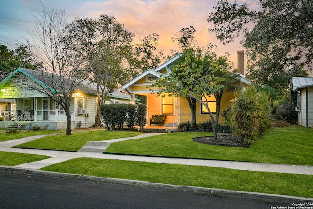 view of front of home with covered porch and a yard