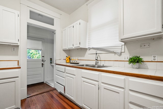 kitchen with sink, white cabinetry, dark wood-type flooring, and tile counters