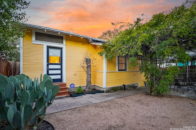 back house at dusk featuring a patio area