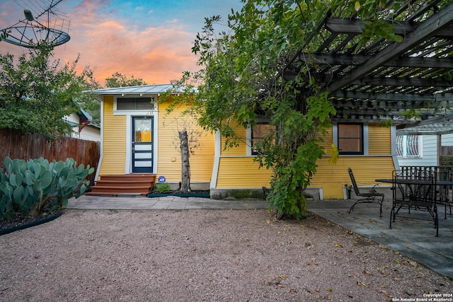 back house at dusk with a patio and a pergola