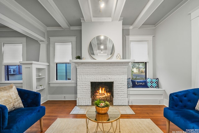 living room featuring crown molding, hardwood / wood-style flooring, beamed ceiling, and a fireplace