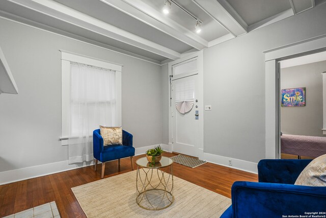 sitting room featuring dark wood-type flooring, beam ceiling, and rail lighting