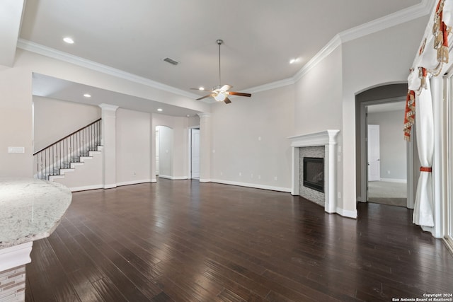 unfurnished living room with dark wood-type flooring, decorative columns, crown molding, and ceiling fan