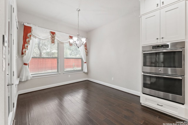 kitchen with stainless steel double oven, dark wood-type flooring, hanging light fixtures, an inviting chandelier, and white cabinets