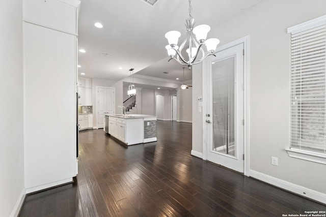 interior space featuring white cabinets, an island with sink, dark wood-type flooring, pendant lighting, and sink