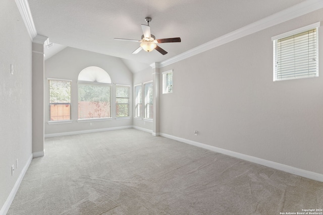 carpeted empty room with crown molding, vaulted ceiling, and ceiling fan