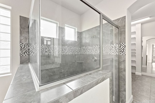 bathroom featuring a shower with door, a healthy amount of sunlight, and tile patterned floors