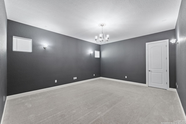 unfurnished room featuring light carpet, a textured ceiling, and an inviting chandelier