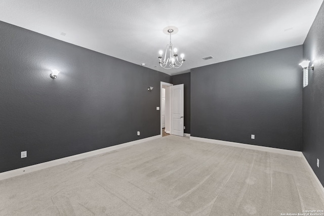 carpeted empty room featuring an inviting chandelier