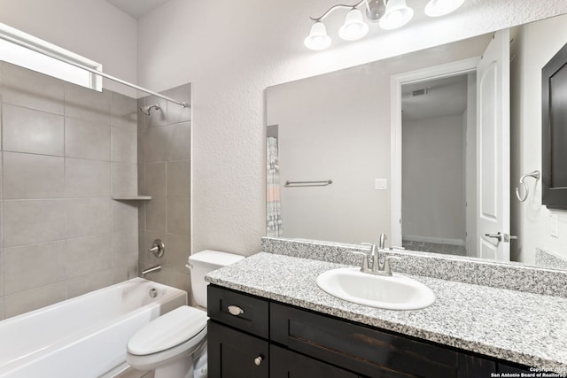 full bathroom with tiled shower / bath, vanity, and toilet