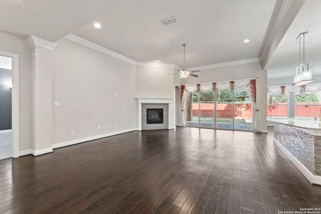 unfurnished living room with decorative columns, ornamental molding, ceiling fan, and dark hardwood / wood-style flooring