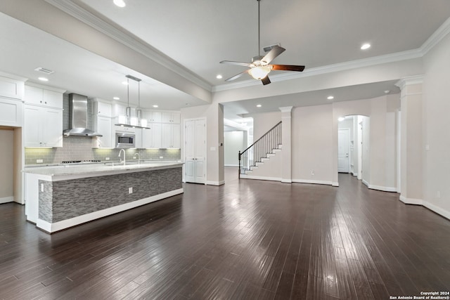 kitchen with a spacious island, wall chimney range hood, and dark hardwood / wood-style flooring