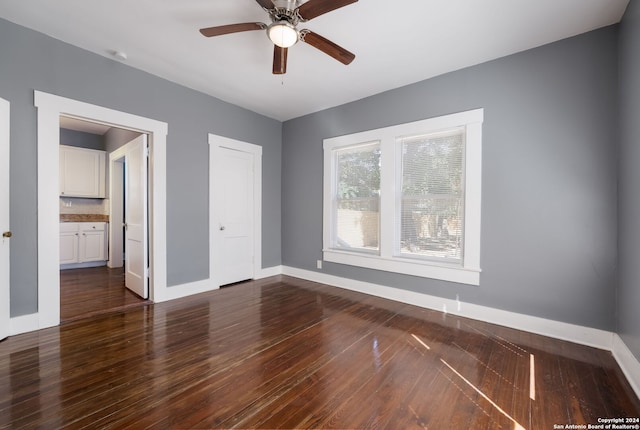 unfurnished bedroom featuring dark wood-type flooring, ceiling fan, and ensuite bath