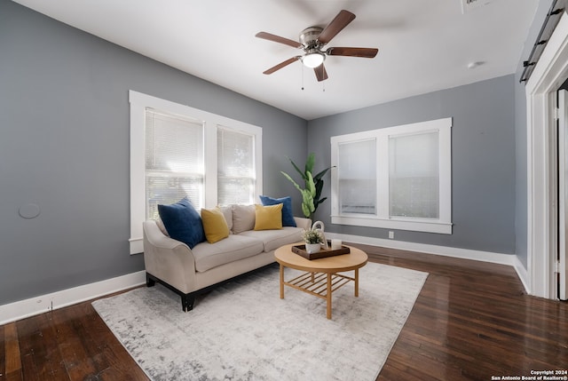 living room featuring ceiling fan, dark hardwood / wood-style flooring, and a barn door