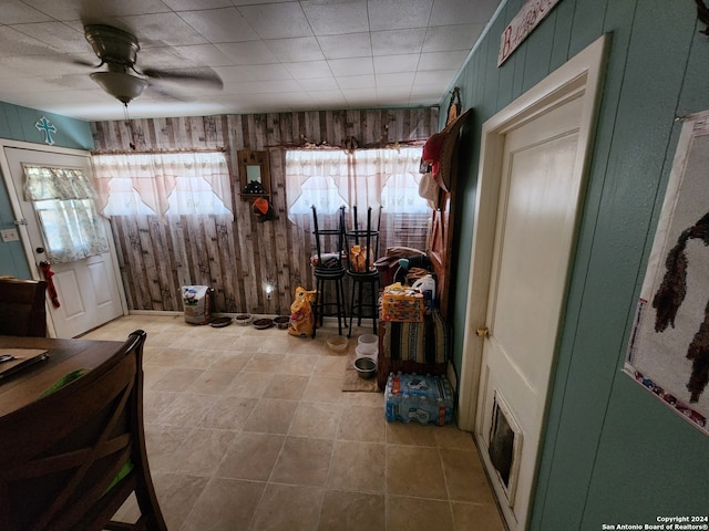 interior space featuring ceiling fan, plenty of natural light, and wooden walls