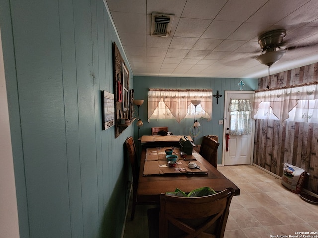 dining space with wooden walls and ceiling fan