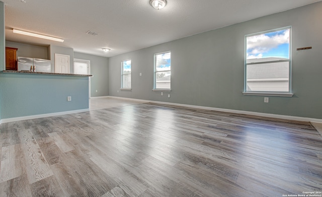 unfurnished room with light hardwood / wood-style flooring and a textured ceiling