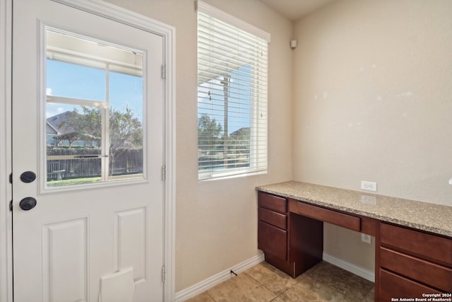 doorway featuring built in desk, light tile patterned floors, and a wealth of natural light