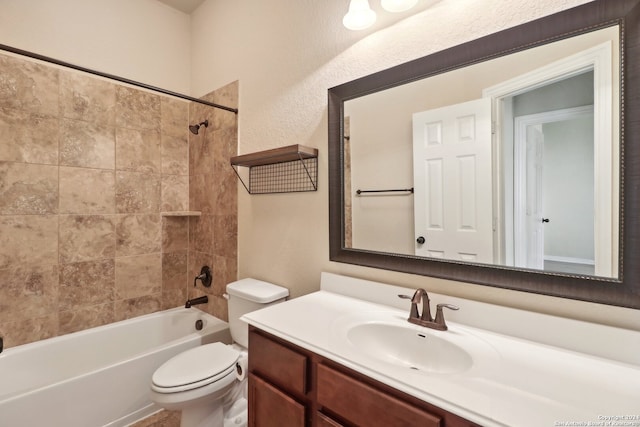 full bathroom featuring tiled shower / bath, vanity, and toilet