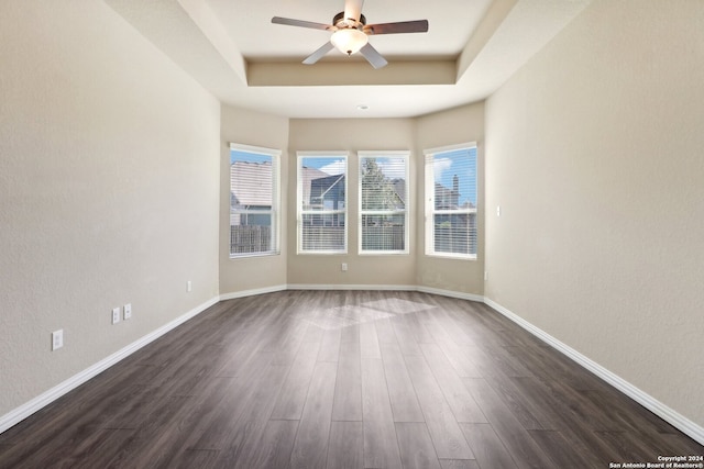 spare room with ceiling fan, a tray ceiling, and dark hardwood / wood-style floors