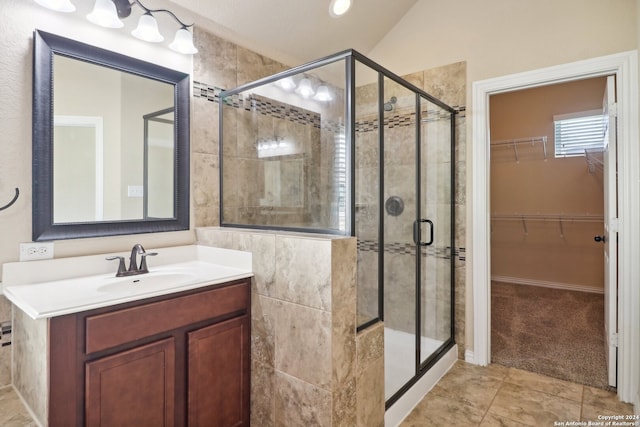 bathroom with vanity, a shower with shower door, lofted ceiling, and tile patterned floors