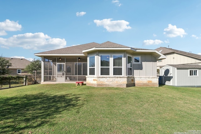 rear view of property featuring a yard, a shed, and a sunroom