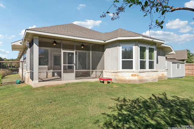 rear view of property with a storage shed, a sunroom, a lawn, and ceiling fan