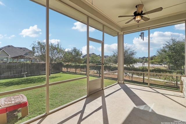 unfurnished sunroom featuring ceiling fan and a healthy amount of sunlight